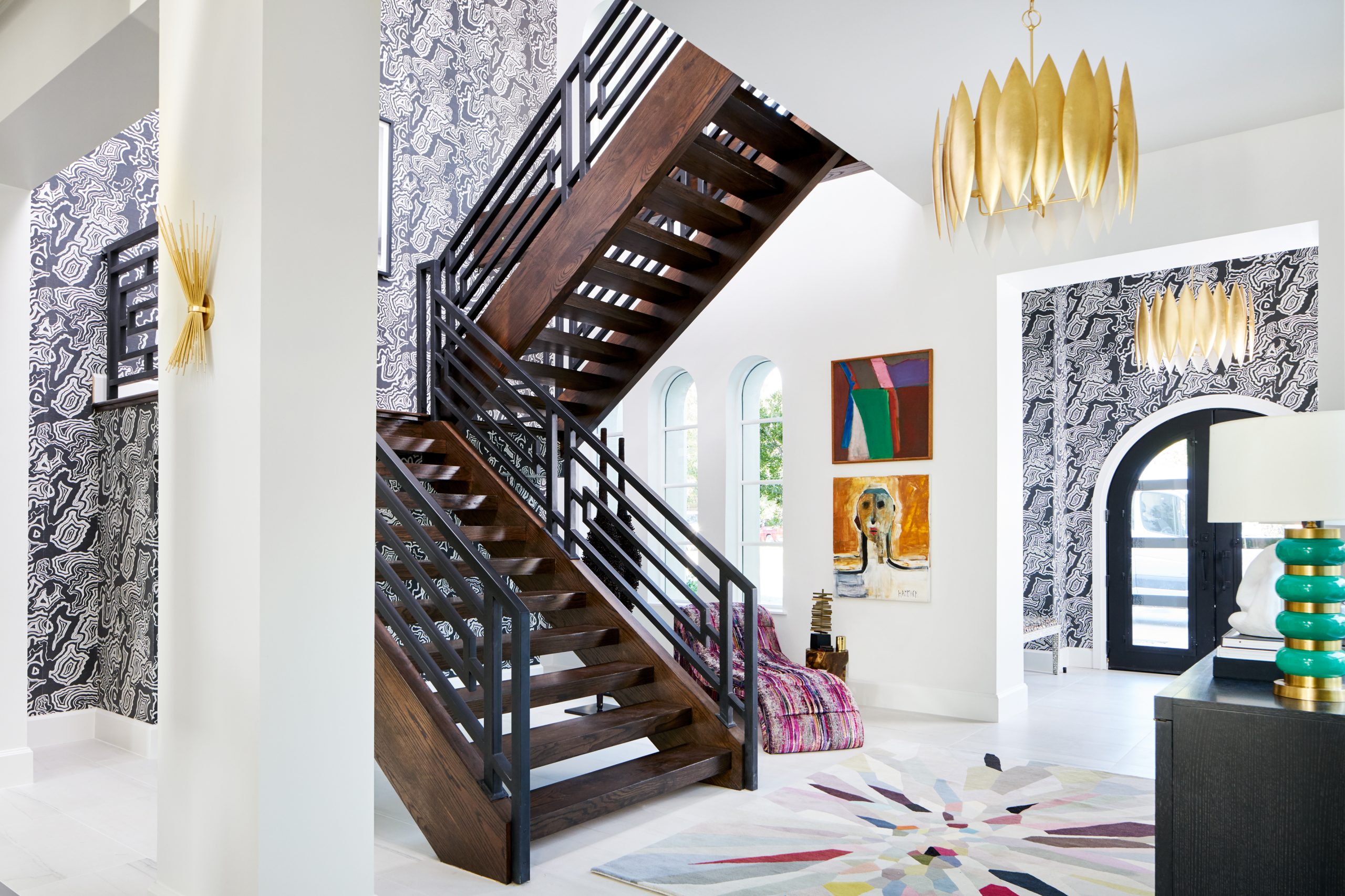 Traditional Home Dallas Showhouse, Bridget Beari Wallcovering, Buscemi wall covering, tina turner art, geometric railing, chaise lounger, s. harris brushstroke, double volume entry, modern staircase, entryway, circa lighting, gold chandelier, green and gold lamp, easel, Jonathan Adler easel, coffee table books, tom ford book, harpers bazaar book, credenza, dark credenza, black credenza, circle accent furniture, bowl, s. harris, drapery, curtains , gold lighting, gold chandelier, colorful rug, the rug company, original art, human form art