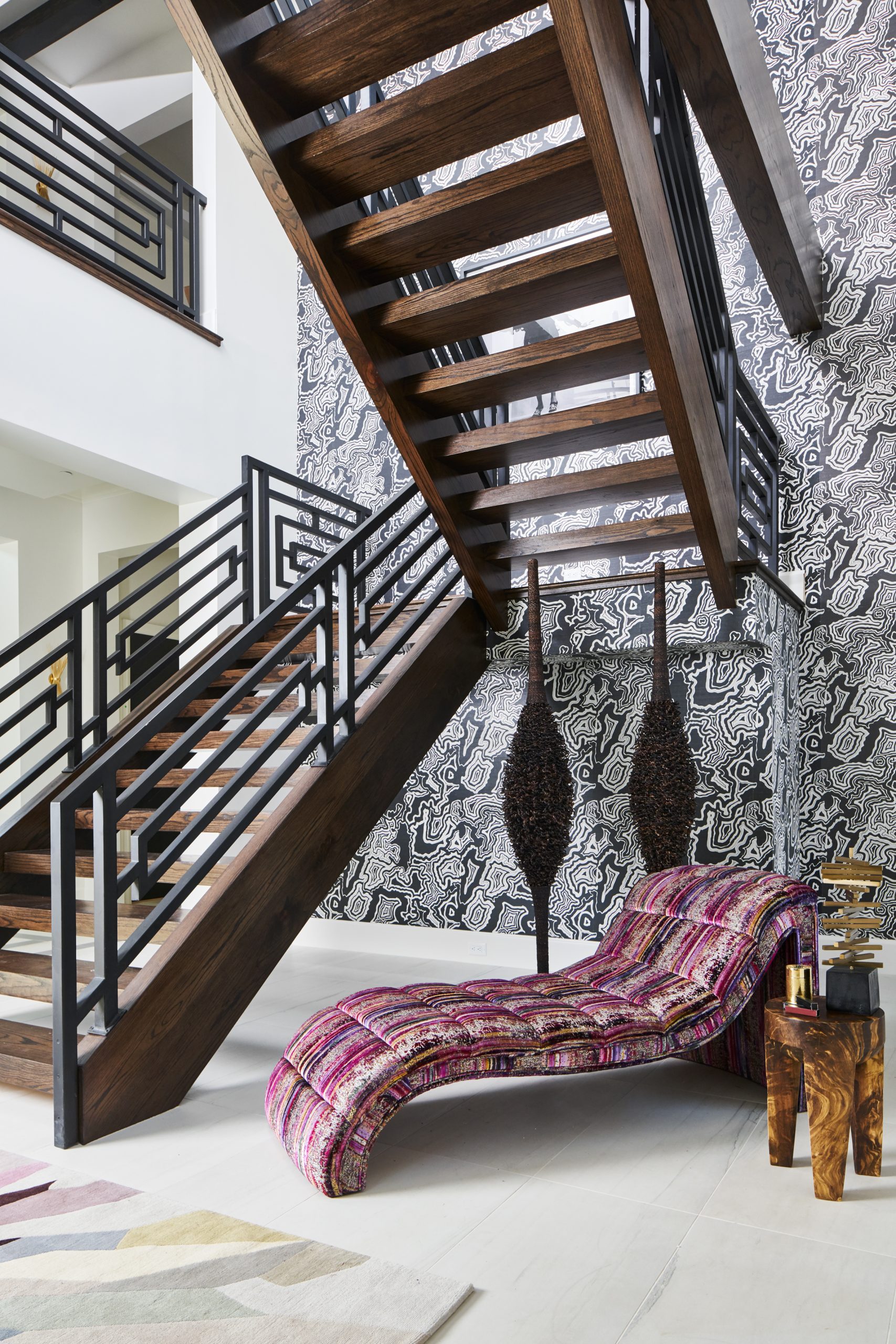 Traditional Home Dallas Showhouse, Bridget Beari Wallcovering, Buscemi wall covering, tina turner art, geometric railing, chaise lounger, s. harris brushstroke, double volume entry, modern staircase, entryway, circa lighting, gold chandelier, urchin sculpture, wood side table, the rug company, colorful rug
