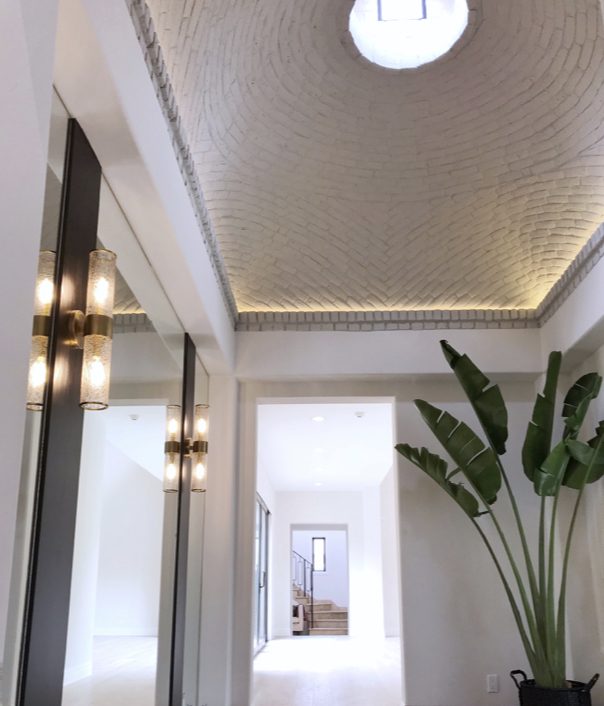 White brick, floor to ceiling mirrors and a bird of paradise brighten an entryway renovation